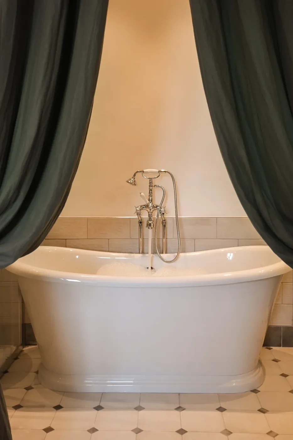 Baignoire îlot encadrée de rideaux verts dans une chambre