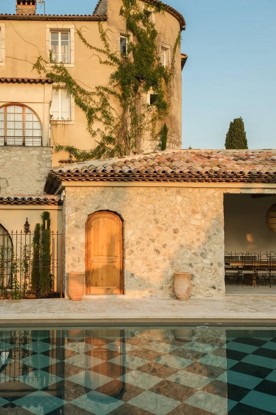Pool house en pierre et piscine à damier au coucher du soleil