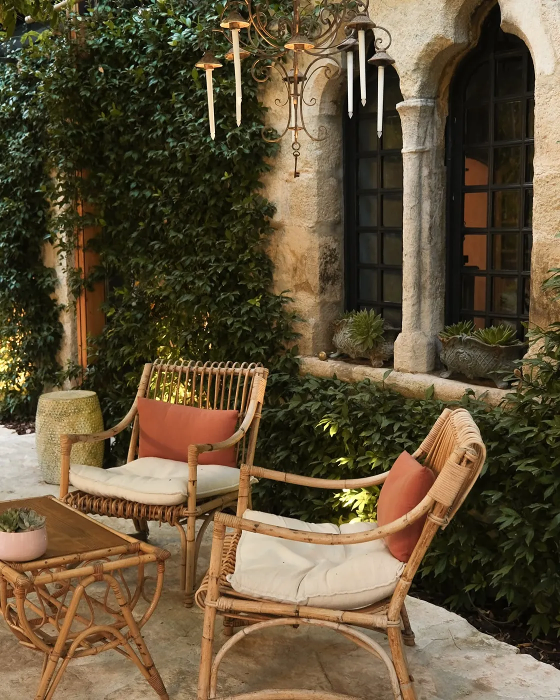 Salon de jardin en rotin sous les arcades en pierre du domaine